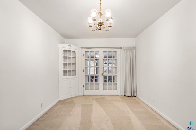 unfurnished room with light colored carpet, a chandelier, and french doors