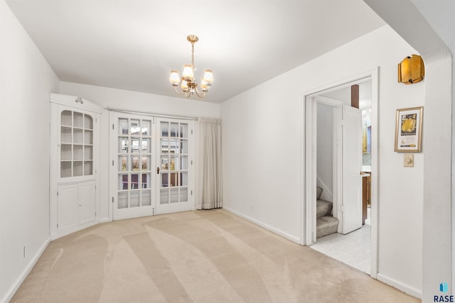 carpeted empty room featuring a chandelier