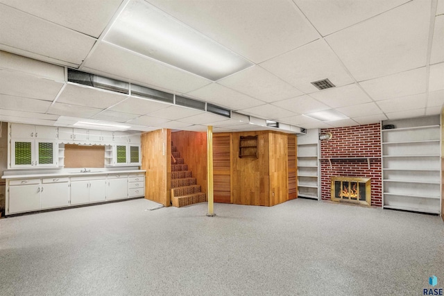 basement featuring a drop ceiling, a brick fireplace, and sink