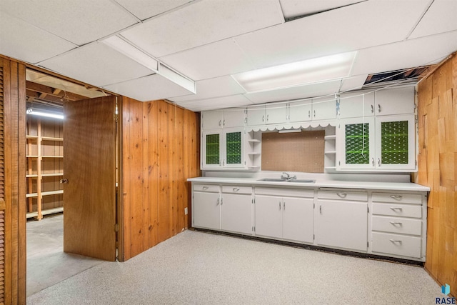 kitchen featuring white cabinets, sink, and wood walls