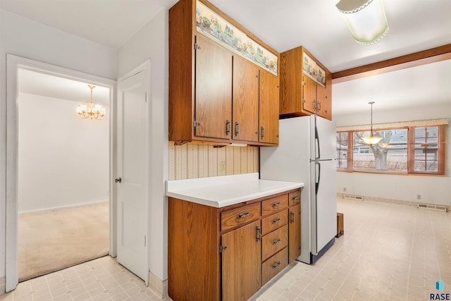 kitchen with white refrigerator, light carpet, hanging light fixtures, and a notable chandelier