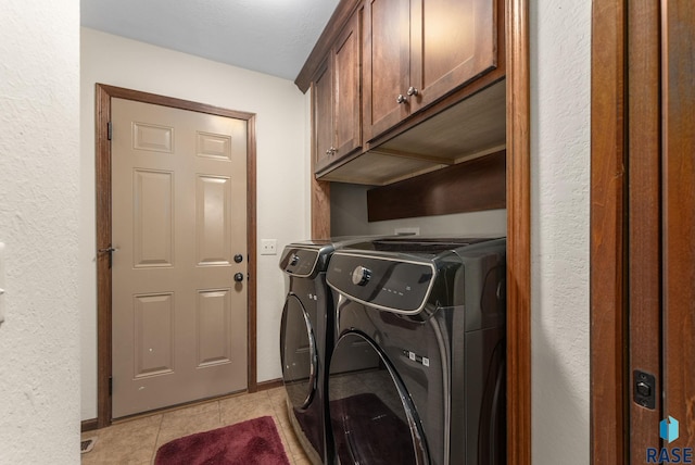 laundry room featuring cabinets, light tile patterned floors, and independent washer and dryer