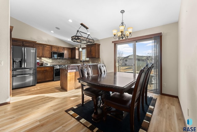 dining space featuring lofted ceiling, a wealth of natural light, a notable chandelier, and light hardwood / wood-style flooring