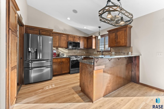 kitchen featuring appliances with stainless steel finishes, decorative backsplash, decorative light fixtures, vaulted ceiling, and kitchen peninsula