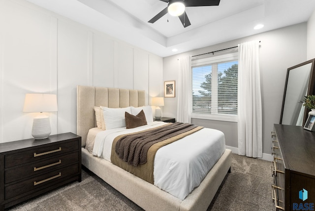 carpeted bedroom with a tray ceiling and ceiling fan