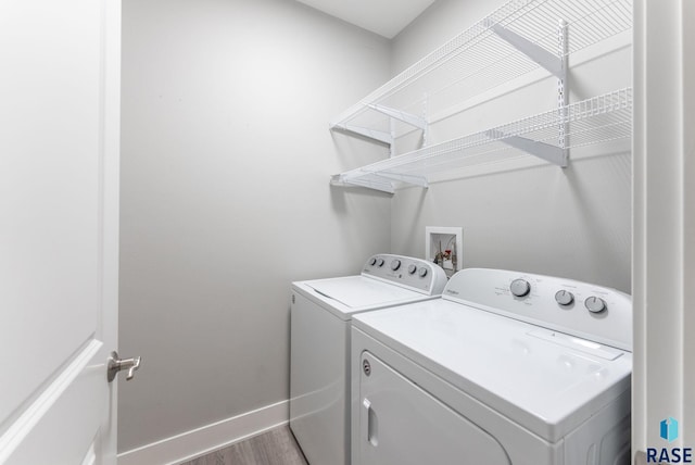 clothes washing area with separate washer and dryer and hardwood / wood-style floors