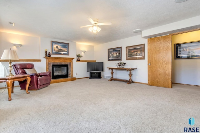 living room featuring a tile fireplace, carpet floors, a textured ceiling, and ceiling fan