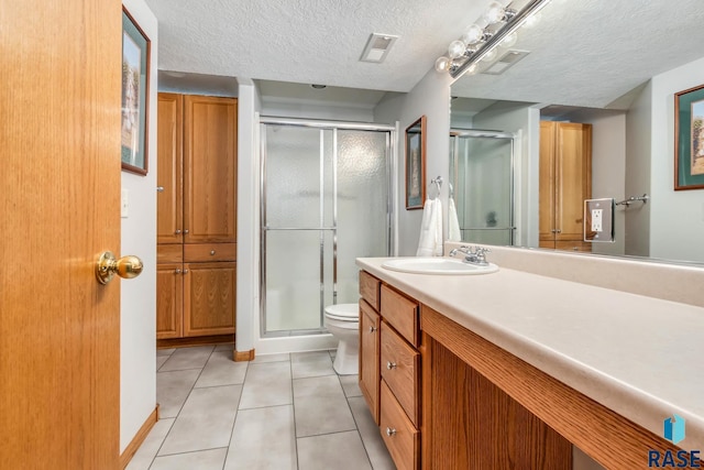 bathroom featuring tile patterned flooring, vanity, walk in shower, toilet, and a textured ceiling