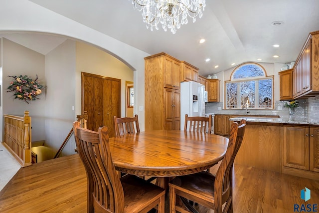 dining area featuring lofted ceiling, sink, a chandelier, and light hardwood / wood-style floors