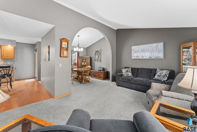 carpeted living room featuring vaulted ceiling and an inviting chandelier