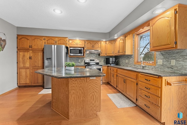 kitchen featuring a kitchen island, appliances with stainless steel finishes, tasteful backsplash, sink, and light hardwood / wood-style flooring