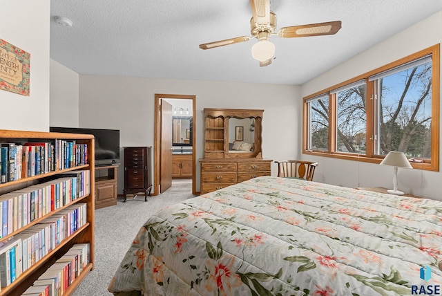 bedroom featuring light carpet, ceiling fan, ensuite bath, and a textured ceiling