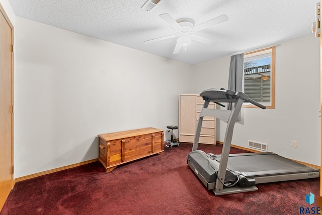 exercise room with dark colored carpet, ceiling fan, and a textured ceiling