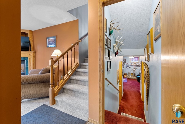 stairway with carpet flooring and a textured ceiling