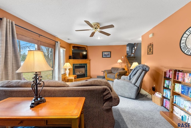 living room featuring ceiling fan, carpet flooring, and a textured ceiling