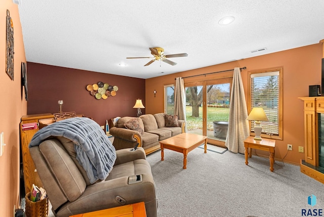 living room with ceiling fan, carpet floors, and a textured ceiling