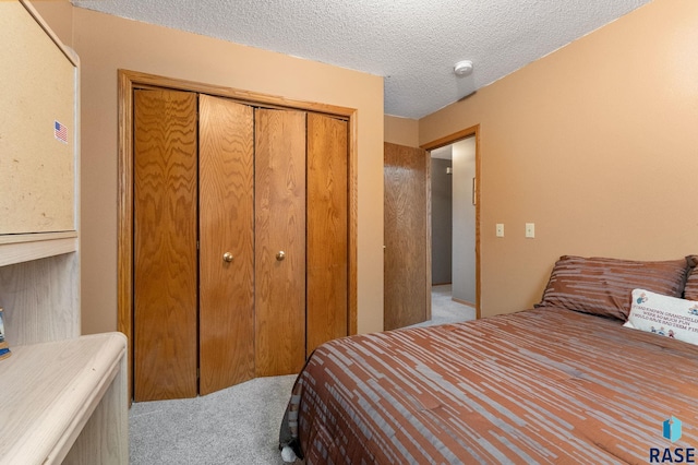 carpeted bedroom with a textured ceiling and a closet