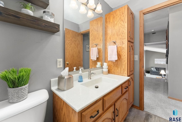 bathroom with vanity, a notable chandelier, and toilet