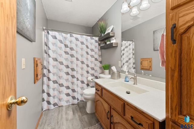 bathroom with vanity, toilet, hardwood / wood-style floors, and a textured ceiling