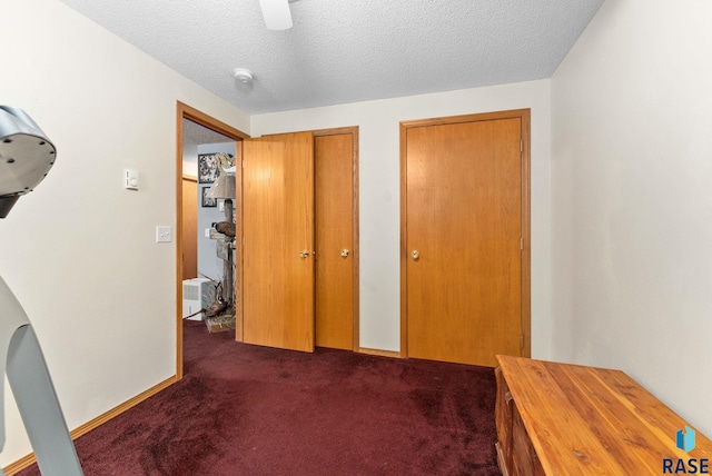 hallway with dark colored carpet and a textured ceiling