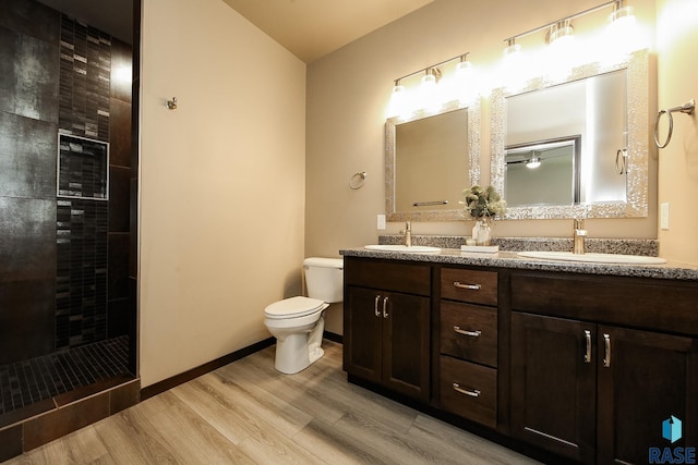 bathroom featuring vanity, hardwood / wood-style floors, toilet, and a tile shower