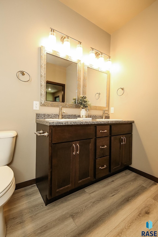 bathroom with wood-type flooring, vanity, and toilet