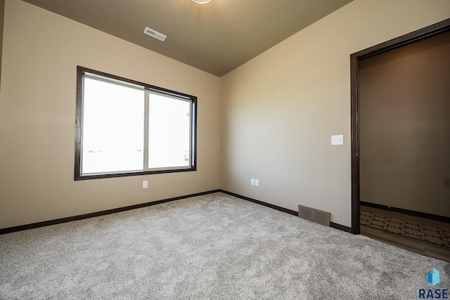 carpeted empty room featuring lofted ceiling