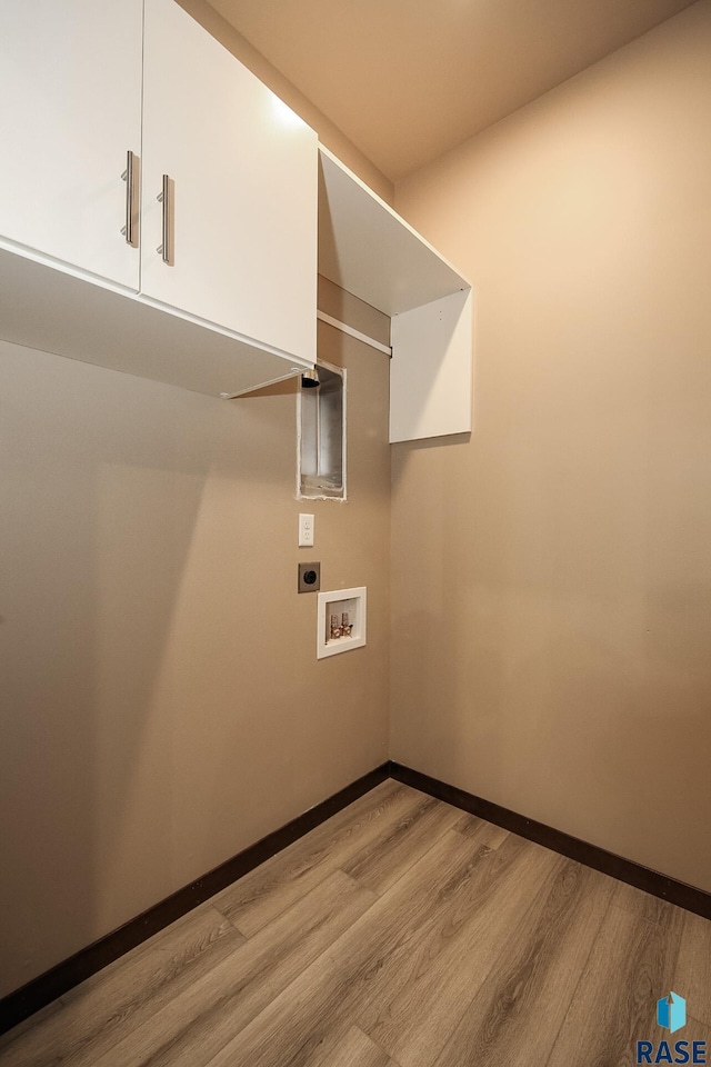 laundry room featuring electric dryer hookup, washer hookup, light hardwood / wood-style flooring, and cabinets