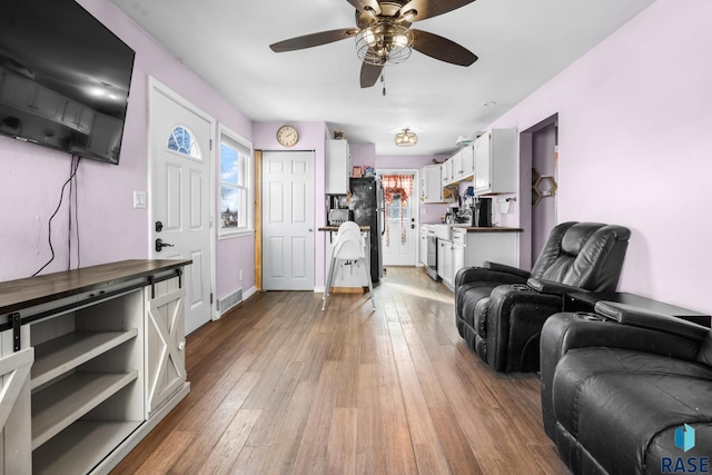 living room featuring plenty of natural light, ceiling fan, and light hardwood / wood-style flooring