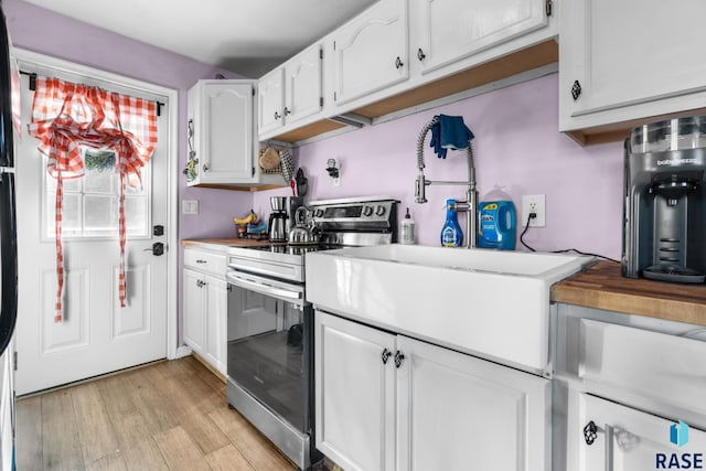 kitchen with white cabinets, butcher block countertops, light hardwood / wood-style floors, and electric range