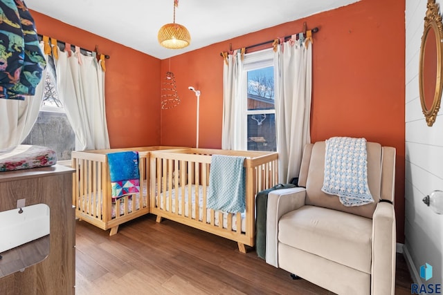 bedroom with a nursery area and hardwood / wood-style floors