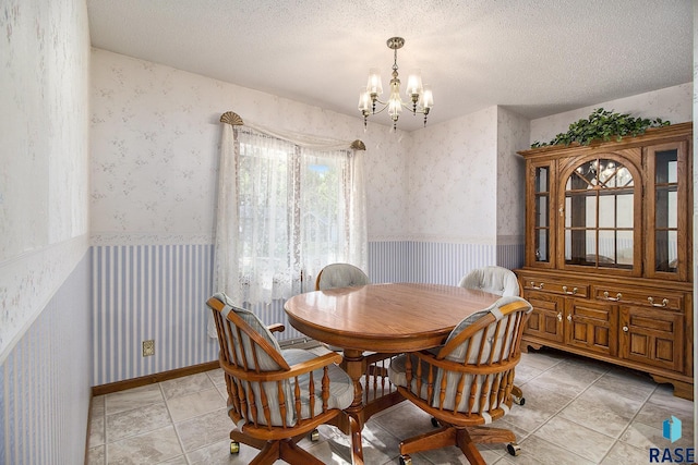 tiled dining space with a chandelier and a textured ceiling