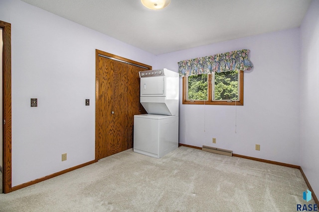 clothes washing area featuring baseboard heating, stacked washer and clothes dryer, and light carpet