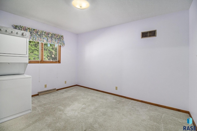 laundry room with a baseboard heating unit, light colored carpet, a textured ceiling, and stacked washer / dryer