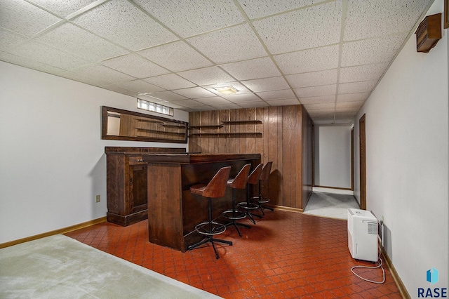 bar with a paneled ceiling and wood walls