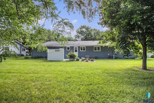 rear view of house with central AC unit and a lawn