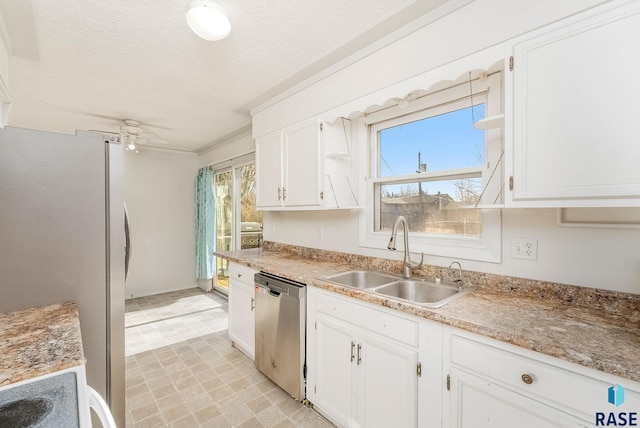 kitchen with appliances with stainless steel finishes, sink, white cabinets, ornamental molding, and a textured ceiling