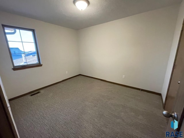 carpeted spare room with a textured ceiling