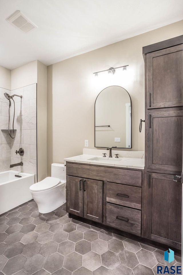 full bathroom with tiled shower / bath, vanity, and toilet