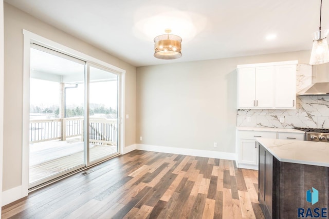 kitchen with wall chimney exhaust hood, tasteful backsplash, pendant lighting, light hardwood / wood-style floors, and white cabinets