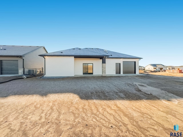 rear view of property featuring a garage and central AC unit