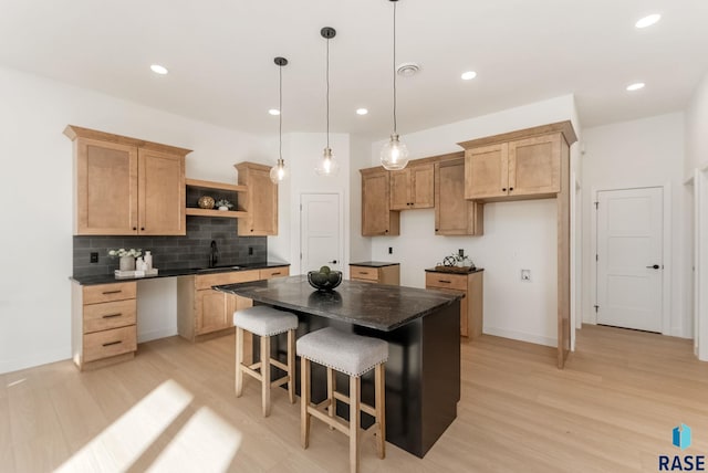 kitchen featuring sink, light hardwood / wood-style flooring, a center island, decorative backsplash, and decorative light fixtures