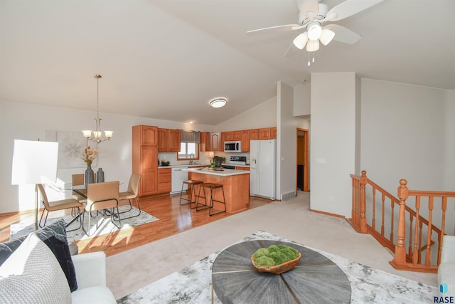 living room featuring sink, ceiling fan with notable chandelier, light hardwood / wood-style flooring, and high vaulted ceiling