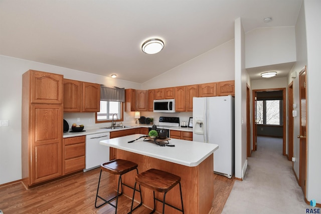 kitchen featuring sink, white appliances, light hardwood / wood-style flooring, a breakfast bar, and a kitchen island