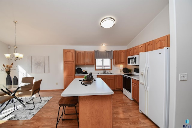 kitchen featuring lofted ceiling, sink, white appliances, hanging light fixtures, and a center island