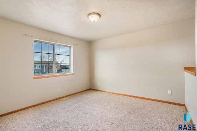 empty room featuring a textured ceiling and carpet