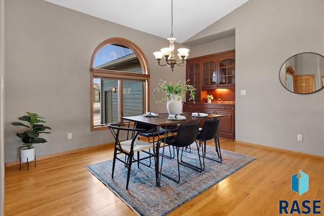 dining space featuring a notable chandelier, vaulted ceiling, and light hardwood / wood-style floors