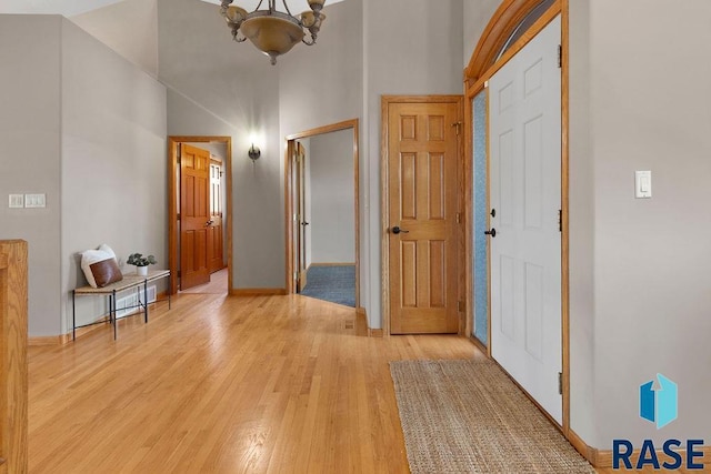 entrance foyer featuring a towering ceiling, an inviting chandelier, and light hardwood / wood-style flooring