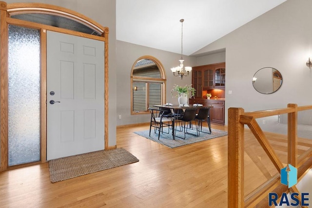 entrance foyer with lofted ceiling, a notable chandelier, and light hardwood / wood-style floors