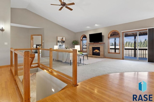 living room featuring wood-type flooring, high vaulted ceiling, ceiling fan, and a fireplace